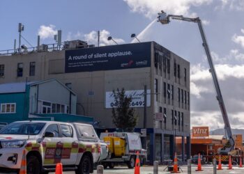 Emergency services dampen down hot spots at the site of the fatal fire at the Loafers Lodge hostel building in the Wellington suburb of Newtown that has killed up to 6 people in Wellington on May 16, 2023. At least six people have been killed in a fire that erupted in the early hours of Tuesday, May 16, 2023 in a four-storey hostel in Wellington, capital city of New Zealand. (Photo by Marty MELVILLE / AFP)