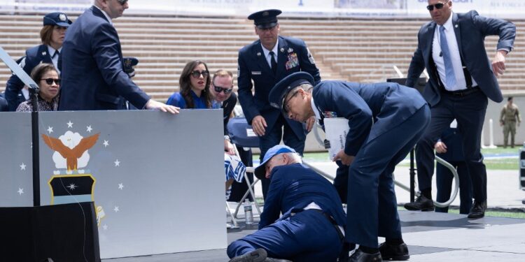 US President Joe Biden is helped up after falling during the graduation ceremony at the United States Air Force Academy, just north of Colorado Springs in El Paso County, Colorado, on June 1, 2023. (Photo by Brendan Smialowski / AFP)