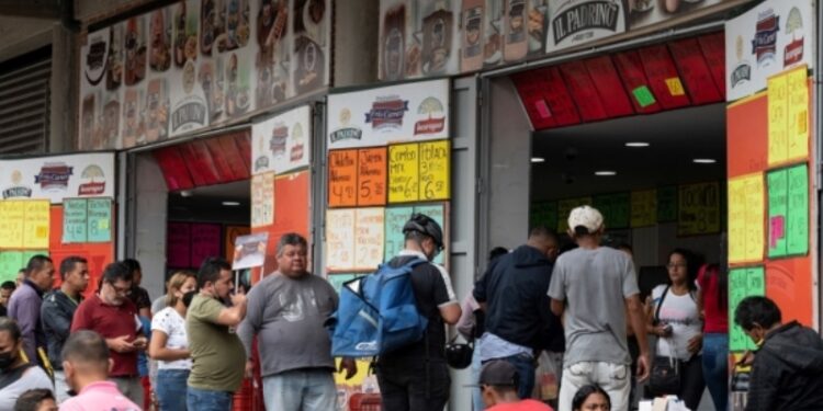 A group of people line up to buy sausages and cheese at a store near the Quinta Crespo municipal market that displays prices in dollars in Caracas on August 25, 2022. (Photo by Yuri CORTEZ / AFP)