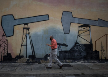 AME6708. CARACAS (VENEZUELA), 31/07/2023.- Un hombre camina frente a un mural en el Complejo MinPetróleo - Petróleos de Venezuela S.A. (Pdvsa), el 27 de julio de 2023 en Caracas (Venezuela). La gallina de los huevos de oro de Venezuela, la industria petrolera, ha estado sobre el tapete en las últimas semanas, cuando candidatos a las primarias opositoras han debatido sobre si convendrá o no su privatización, una opción que algunos aspirantes tienen como meta en caso de llegar a la Presidencia. EFE/ MIGUEL GUTIÉRREZ
