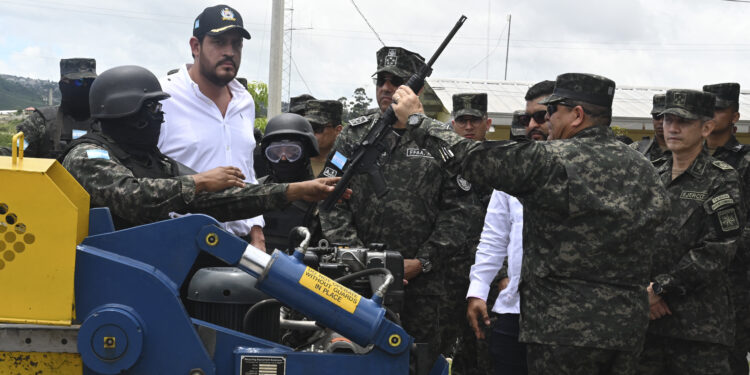 Defense Minister Jose Manuel Zelaya (2nd-L) watches as members of the army proceed to destroy high-powered firearms seized from Barrio 18 and Mara Salvatrucha (MS-13) gangs in Honduran prisons after President Xiomara Castro ordered to take control of them, at the headquarters of the Military Police of Public Order in Tegucigalpa on July 10, 2023. (Photo by Orlando SIERRA / AFP)