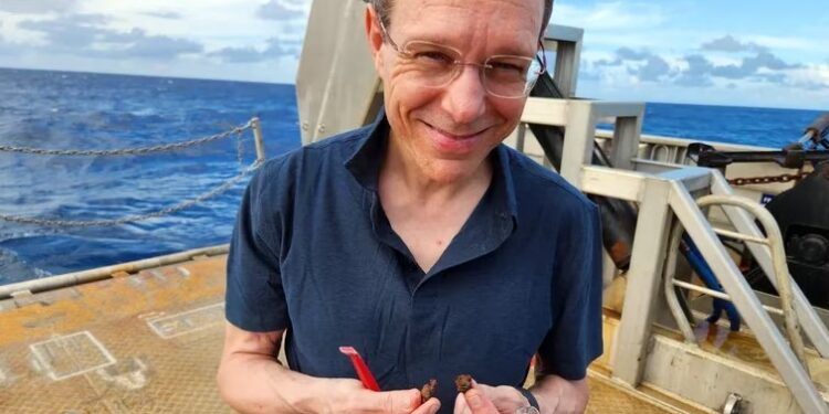 Avi Loeb con fragmentos metálicos hallados en el fondo del mar. Su trabajo despierta escepticismo entre colegas.