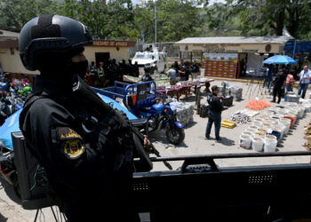 A member of the Anti-Extortion and Kidnapping Group (CONAS) stands guard as confiscated weapons and ammunition are displayed during a press conference after authorities seized control of the prison in Tocoron, Aragua State, Venezuela, on September 21, 2023. Venezuela said Wednesday it had seized control of a prison from the hands of a powerful gang with international reach, in a major operation involving 11,000 members of its security forces. (Photo by YURI CORTEZ / AFP)