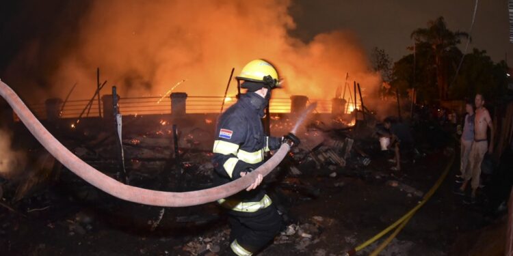 A firefighter works during a large fire in the Ricardo Brugada neighborhood, known as "La Chacarita", in the vicinity of the Cabildo in Asuncion on October 6, 2023. (Photo by Daniel DUARTE / AFP)