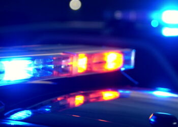 Emergency lights flashing on police cars at night at the scene of an accident or crime. Focus shifts from lights in the foreground to the lights in the background.