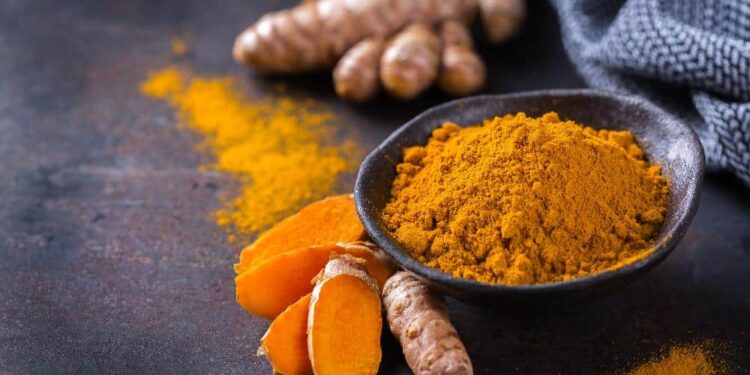 Food and drink, diet nutrition, health care concept. Raw organic orange turmeric root and powder, curcuma longa on a cooking table. Indian oriental low cholesterol spices. Copy space background