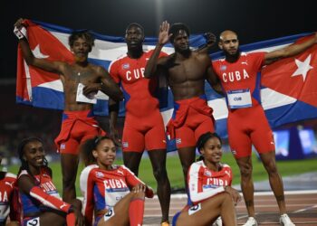 Cuba's men's team (top) celebrates next to the women's team after winning the silver and gold medals, respectively, in the 4 x 100m relay finals of the Pan American Games Santiago 2023 at the National Stadium in Santiago on November 2, 2023. (Photo by MAURO PIMENTEL / AFP)