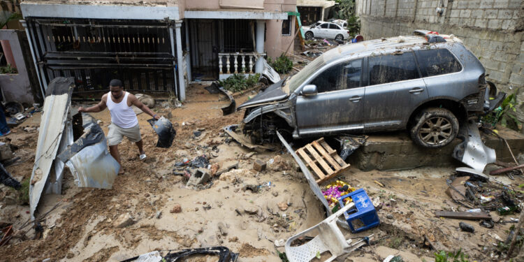 SANTO DOMINGO (REPÚBLICA DOMINICANA), 19/11/2023.- Un hombre recupera pertenencias junto a varios vehículos que fueron arrastrados por la corriente, hoy en Santo Domingo (República Dominicana). Las lluvias torrenciales que afectan a República Dominicana desde el viernes han obligado a desplazar de sus hogares a cerca de 8.000 personas, dañado viviendas e infraestructuras y más de una docena de muertos, aunque las autoridades solo confirmaron nueve fallecidos. EFE/Orlando Barría