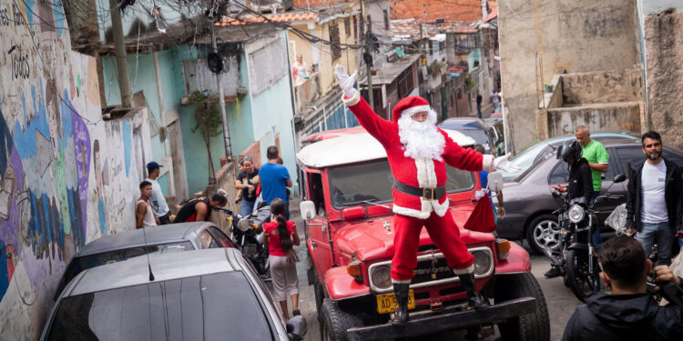 AME4589. CARACAS (VENEZUELA), 15/12/2023.- Un Papá Noel trabaja hoy durante la jornada "Un Juguete, una Buena Noticia", en la parroquia Petare en Caracas (Venezuela). Una treintena de trabajadores de la prensa de Venezuela, acompañados por Santa Claus, entregaron este viernes más de 400 regalos a niños que viven en varios sectores de Petare, la favela más grande del país, como parte de la iniciativa 'Un juguete, una buena noticia', promovida por periodistas. EFE/ Rayner Peña R