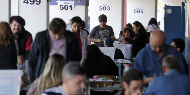 AME4834. SANTIAGO (CHILE), 17/12/2023.- Ciudadanos hacen fila para votar en la jornada del plebiscito constitucional hoy, en el estadio Nacional de Santiago (Chile). Más de 15,4 millones de chilenos deciden si aprueban o rechazan una nueva propuesta de Constitución que sustituya a la actual, vigente desde 1981, en plena dictadura de Augusto Pincochet (1973-1990), pero reformada decenas de veces en democracia, especialmente en 2005, durante la Presidencia de Ricardo Lagos (2000-2006). EFE/ Elvis González