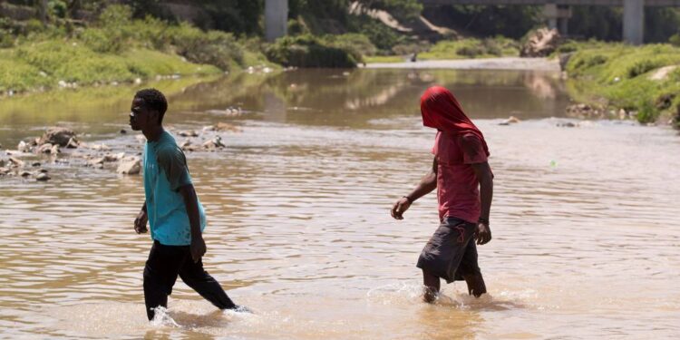 Dos haitianos cruzan el río Masacre, la frontera natural entre República Dominicana y Haití. EFE