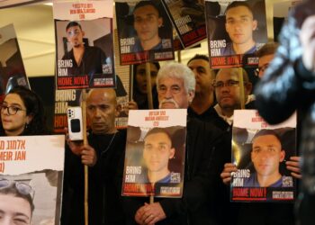 Relatives and supporters hold placards bearing portraits of Israeli hostages held in Gaza since the October 7 attacks by Hamas in southern Israel, during a rally calling for their release and marking their nearly 100 days of captivity, in Tel Aviv on January 13, 2024. The placards (front) show Matan Angrest, 21. (Photo by AHMAD GHARABLI / AFP)