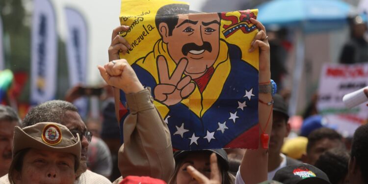 AME2269. CARACAS (VENEZUELA), 25/03/2024.- Una persona levanta un cartel con un dibujo del presidente venezolano, Nicolás Maduro, durante una concentración de simpatizantes del oficialismo que se reúnen este lunes para mostrar su apoyo y acompañar a su candidato a las próximas elecciones del 28 de julio, el actual mandatario Nicolás Maduro, a oficializar su aspiración ante el Consejo Nacional Electoral (CNE), en Caracas (Venezuela). El proceso de presentación de candidaturas para las presidenciales concluye este lunes, con la inscripción de Maduro, mientras que la oposición mayoritaria espera poder postular a Corina Yoris, su aspirante ante la inhabilitación de María Corina Machado, ganadora de las primarias de octubre. EFE/ Miguel Gutiérrez