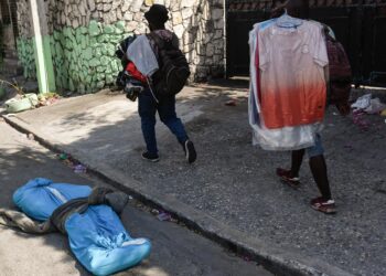 ATENCIÓN EDITORES: CONTENIDO GRÁFICO EXPLÍCITO - AME403. PUERTO PRÍNCIPE (HAITÍ), 20/03/2024.- Transeúntes pasan junto al cadáver de una persona cubierto por telas en la calle, este miércoles, en Puerto Príncipe (Haití). Al menos siete cadáveres aparecieron este miércoles en las calles de Petion-ville, en las colinas de la capital de Haití, dos días después de que al menos otras quince personas fueran encontradas muertas en la misma zona. Los cuerpos aparecieron algunos con disparos y otros carbonizados, mientras los servicios encargados de ello recogían e introducían en ataúdes los cadáveres, como pudo comprobar EFE. EFE/ Johnson Sabin