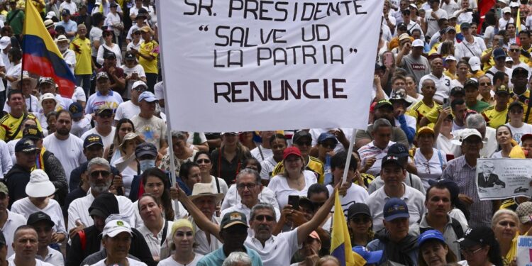 A demonstrator holds a sign that reads "Mr. President, save the homeland. Resign" during a protest against the government of Colombian President Gustavo Petro over health and pension reforms in Cali, Colombia, on April 21, 2024. Hundreds of thousands of people are protesting this Sunday in Colombia's main cities, in the largest demonstration faced by the government of Gustavo Petro since he came to power twenty months ago and at a time when his popularity is in the red. (Photo by JOAQUIN SARMIENTO / AFP)