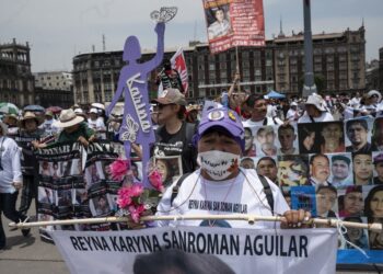 Mothers and relatives of missing persons in different states of Mexico carry signs with photos of their loved ones while participating in a march to demand that the government clarify the disappearances within the framework of Mother's Day in front of the National Palace at El Zocalo Square in Mexico City on May 10, 2024. (Photo by Yuri CORTEZ / AFP)