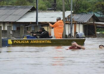 Agentes de policía revisan una casa mientras habitantes vadean una calle inundada por tormentas derivadas de un ciclón en Passo Fundo, en el estado de Rio Grande do Sul, Brasil, el lunes 4 de septiembre de 2023. (AP Foto/Diogo Zanatta-Futura Press)