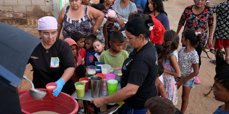 People receive food from Carolina Leal, director and founder of the foundation Alimentando Suenos, in Maracaibo, Venezuela June 12, 2024. REUTERS/Gaby Oraa/File Photo