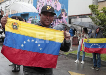 AME5600. BOGOTÁ (COLOMBIA), 28/07/2024.- Ciudadanos venezolanas posan con la bandera de su país frente al puesto de votación en las elecciones presidenciales de Venezuela este domingo, en Bogotá (Colombia). "Esperamos que se cumpla con la con la ley, que se cumple con el mandato de los ciudadanos y que se cumpla con la democracia", explicó emocionado a EFE Álvaro Carranque, uno de los primeros venezolanos que depositó su voto en Bogotá en los comicios presidenciales de este domingo. EFE/ Carlos Ortega