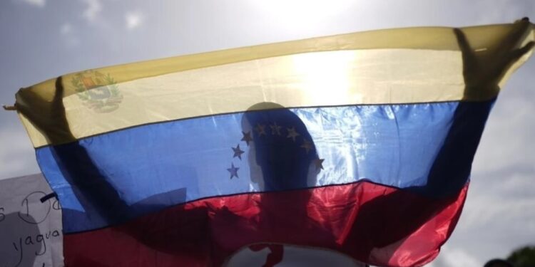 Un familiar de un preso en huelga de hambre sostiene una bandera venezolana durante una protesta en la avenida Bolívar en Caracas, Venezuela, el miércoles 12 de junio de 2024. AP - Ariana Cubillos