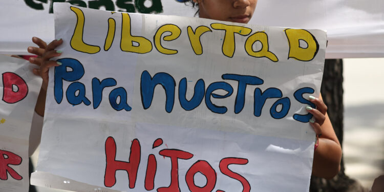 AME2885. CARACAS (VENEZUELA), 26/09/2024.- Una mujer sostiene un cartel en una manifestación de familiares de adolescentes detenidos durante las protestas contra los resultados de elecciones presidenciales en Venezuela este jueves, en Caracas (Venezuela). Un grupo de familiares de detenidos en Venezuela pidió a la Fiscalía que revise los casos de ocho menores de edad apresados en el contexto de las protestas poselectorales, ya que, según sus allegados, "son inocentes" y "están siendo injustamente criminalizados". EFE/ Miguel Gutiérrez