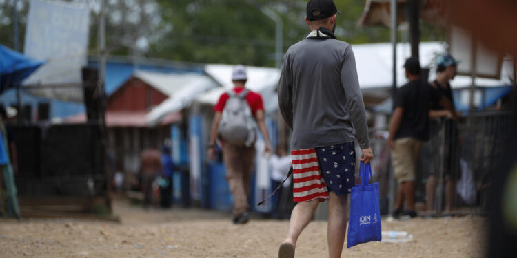 ACOMPAÑA CRÓNICA: PANAMÁ CRISIS MIGRATORIA AME2908. LAJAS BLANCAS (PANAMÁ), 26/09/2024.- Un migrante camina vistiendo una prenda impresa con la bandera de los Estados Unidos en la Estación Temporal de Recepción Migratoria (ETRM), este jueves en Lajas Blancas, Darién (Panamá) Los venezolanos siguen siendo mayoría entre los migrantes que atraviesan la selva del Darién, la frontera natural entre Panamá y Colombia, rumbo a Norteamérica, y algunos de ellos hablan de "la peor trampa del mundo", después de que el pasado 28 de julio en las elecciones en Venezuela se proclamó, sin que se difundieran las actas, la victoria del mandatario Nicolás Maduro. EFE/Bienvenido Velasco