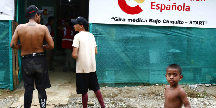 AME6366. BAJO CHIQUITO (PANAMÁ), 11/10/2024.- Personas esperan frente a un puesto de salud este martes, en Bajo Chiquito (Panamá). Después de días de caminata para cruzar la peligrosa selva del Darién, frontera entre Colombia y Panamá, cientos de migrantes llegan a una remota población indígena, donde la cooperación española ha instalado una clínica para atender sobre todo a niños y mujeres, muchos arrastrando los pies llenos de úlceras, agotados, o incluso víctimas de abusos sexuales. EFE/ Moncho Torres