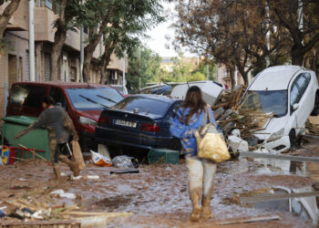 CATARROJA (VALENCIA), 31/10/2024.- Varias personas caminan entre el lodo acumulado en las calles a causa de las intensas lluvias caídas por la fuerte dana, este jueves en Catarroja. Catarroja, una de las localidades afectadas por la dana que asoló este martes la provincia de Valencia, se afana por restablecer los suministros cortados a consecuencia del temporal y en ofrecer ayuda humanitaria a los vecinos.EFE/Manuel Bruque