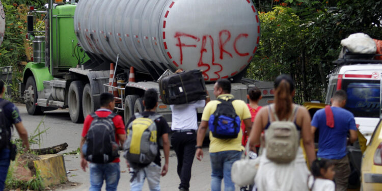 AME1809. BOGOTÁ (COLOMBIA), 21/01/2025.- Fotografía de archivo del 16 de agosto de 2023 de personas caminando junto a un camión con la frase "FARC 33" en la Vereda Santa Rosa, en Catatumbo (Colombia). Los enfrentamientos entre la guerrilla Ejército de Liberación Nacional (ELN) y una disidencia de las FARC en la región colombiana del Catatumbo, con al menos 80 muertos y cerca de 20.000 desplazados, han hecho que el país vuelva a mirar a esa región del noreste que lleva décadas sometida a la violencia de grupos guerrilleros, paramilitares y narcotraficantes. EFE/ Mario Caicedo /ARCHIVO