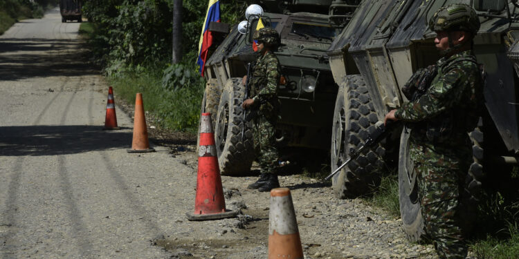 Army soldiers stand guard on a road as forces patrol in Tibu, Norte de Santander province, Colombia, on January 21, 2025, after recent clashes between rival left-wing guerrillas. Colombia vowed "war" against left-wing guerrillas Monday, declaring a state of emergency and deploying thousands of soldiers to contain violence that killed at least 100 people and threatens to scupper the country's fragile peace process. (Photo by Schneyder Mendoza / AFP)