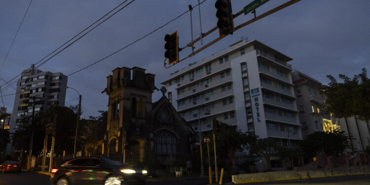 A car navigates through an intersection without stop lights in San Juan, Puerto Rico after a major power outage hit the island on December 31, 2024. - A major power outage plunged much of Puerto Rico into darkness Tuesday, with the US island territory's electric utility saying restoration could take up to two days. The "island-wide blackout" began at 5:30 am (0930 GMT), Luma Energy said in a social media statement. (Photo by Ricardo ARDUENGO / AFP)