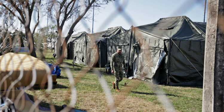 A member of the Mexican Navy walks past a row of tents as they begin building a temporary shelter on the border in Matamoros, Tamaulipas state, Mexico on January 22, 2025, ahead of US President Donald Trumps promised deportations. (Photo by QUETZALLI BLANCO / AFP)