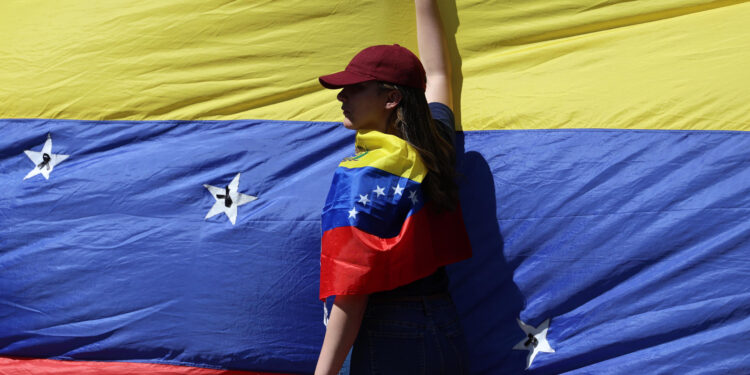 AME9799. CARACAS (VENEZUELA), 09/01/2025.- Una seguidora de la líder antichavista María Corina Machado sostiene la bandera de Venezuela este jueves, en una manifestación en Caracas (Venezuela). Machado expresó, cuando salió de la clandestinidad para participar en una protesta en Caracas, que Venezuela "superó el miedo" al estar en las calles para -aseguró- defender el reclamado triunfo de Edmundo González Urrutia en las elecciones del pasado julio, en las que Nicolás Maduro fue proclamado ganador por el organismo comicial. EFE/ Miguel Gutiérrez