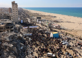 People walk along Gaza's coastal al-Rashid Street to cross the Netzarim corridor from the southern Gaza Strip into the north on January 27, 2025. Displaced Palestinians began returning to northern Gaza on January 27, an official at the territory's Hamas-run Interior Ministry told AFP, after a breakthrough in negotiations between Hamas and Israel. (Photo by Omar AL-QATTAA / AFP)