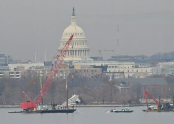 A crane removes airplane wreckage from the Potomac River, where American Airlines flight 5342 collided with a US Army military helicopter, near Ronald Reagan Washington National Airport in Arlington, Virginia, on February 3, 2025. Operations to salvage the wreckage from a deadly collision between a US Army helicopter and a passenger jet continued as rescuers said 55 victims had so far been identified. Dozens of victims have been pulled from the icy Potomac River, and rescuers voiced confidence that those remaining would be retrieved in the massive operation to recover the plane that collided in midair with a Black Hawk military helicopter. (Photo by ROBERTO SCHMIDT / AFP) / ALTERNATE CROP